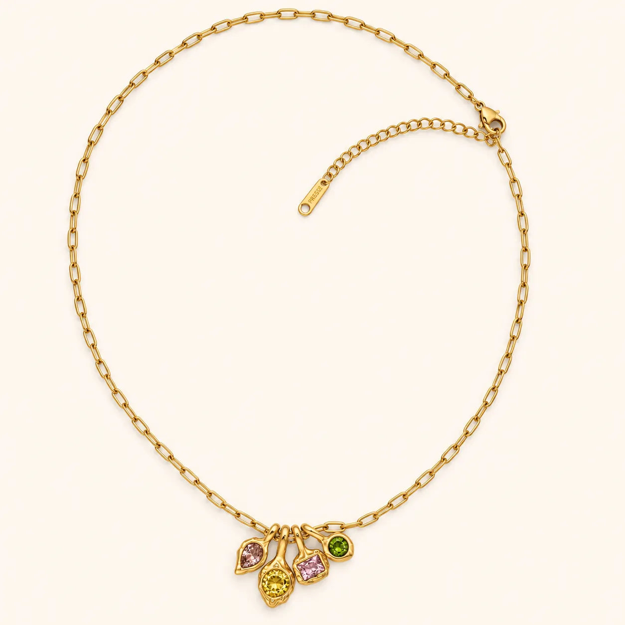 A gold chain necklace with a multi-drop pendant featuring three teardrop-shaped gemstones in pink, yellow, and green, displayed on a light cream background.